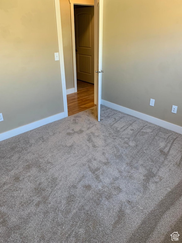 empty room featuring carpet and baseboards