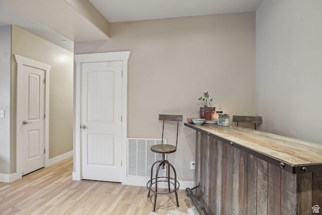bar with baseboards, wood finished floors, and visible vents