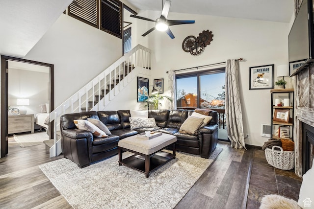living area with wood finished floors, a fireplace, ceiling fan, and stairs
