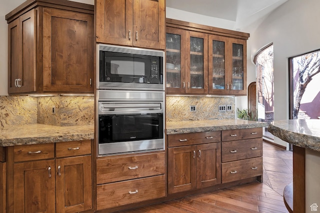 2336 W Entrada Trl Unit 44, St George, UT 84770 - kitchen with oven, black microwave, decorative backsplash, glass insert cabinets, and light stone counters