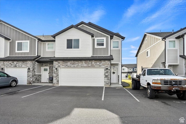 townhome / multi-family property featuring a garage, stone siding, board and batten siding, and driveway