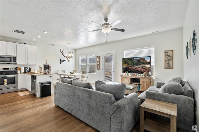 292 N 100 W, Morgan, UT 84050 - living room featuring visible vents, a textured ceiling, light wood-style flooring, and ceiling fan with notable chandelier