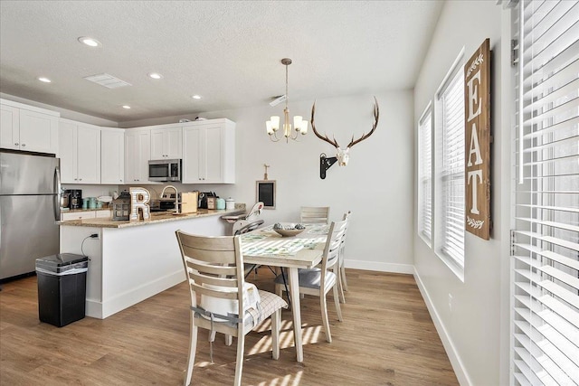 292 N 100 W, Morgan, UT 84050 - kitchen with an inviting chandelier, a peninsula, light wood finished floors, and appliances with stainless steel finishes