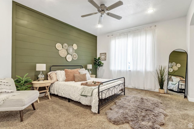 carpeted bedroom with wooden walls, ceiling fan, baseboards, arched walkways, and recessed lighting