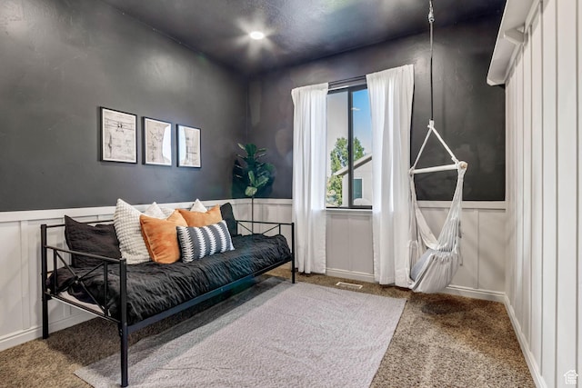 sitting room featuring carpet flooring, a decorative wall, and a wainscoted wall
