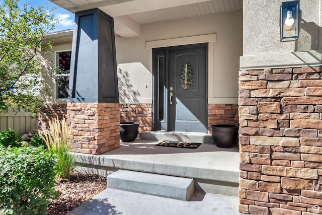 view of exterior entry with stucco siding and stone siding