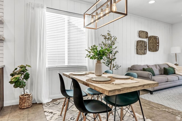 dining area with tile patterned floors, a decorative wall, wooden walls, and recessed lighting