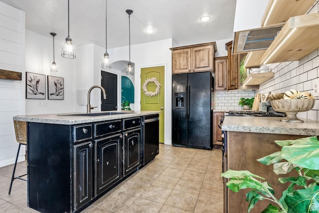 kitchen with black refrigerator with ice dispenser, dishwasher, dark cabinetry, a sink, and light tile patterned floors