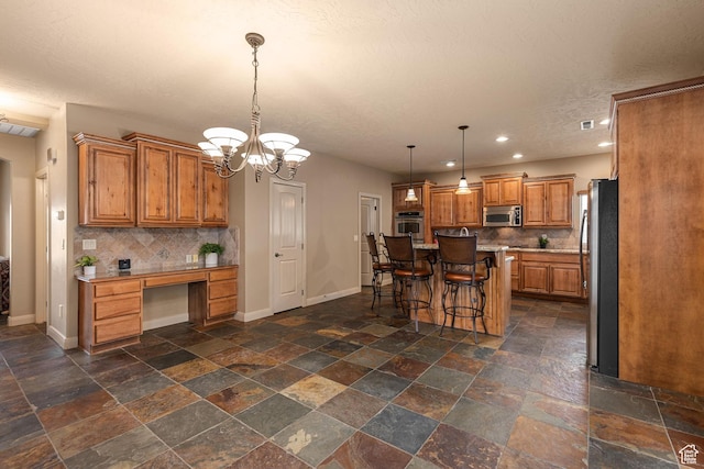 1815 N Red Mountain Dr, Santa Clara, UT 84765 - kitchen with brown cabinetry, appliances with stainless steel finishes, built in study area, and baseboards