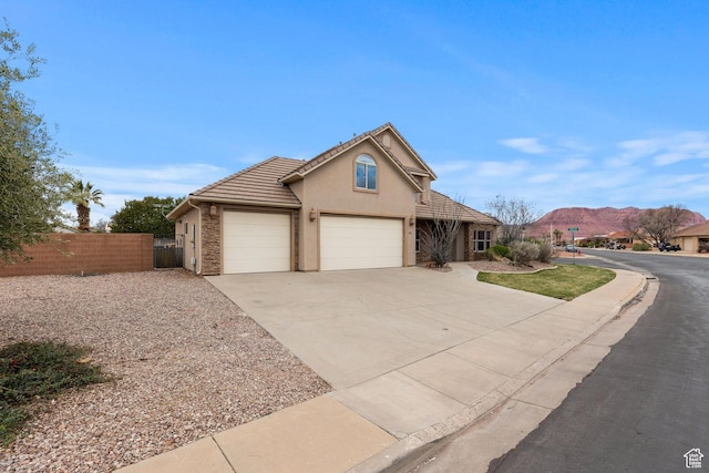 1815 N Red Mountain Dr, Santa Clara, UT 84765 - view of front of home with stucco siding, driveway, a tile roof, fence, and an attached garage