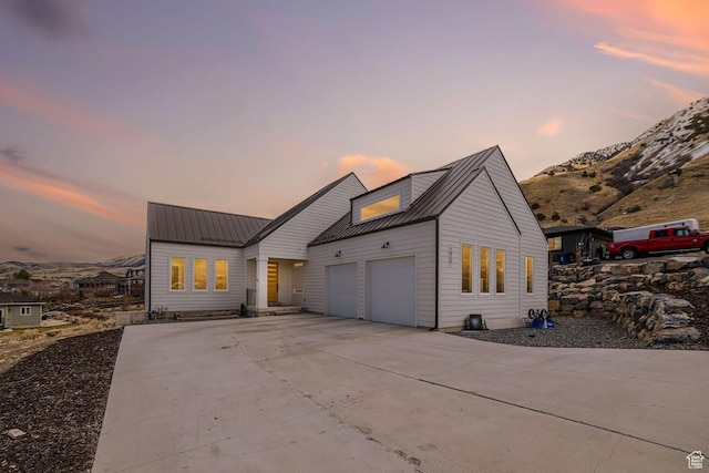 modern farmhouse style home featuring a mountain view, driveway, metal roof, and a garage