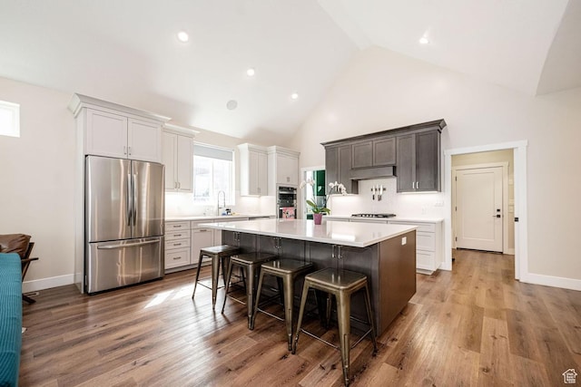 1959 E Deer Crest Cir N, Logan, UT 84341 - kitchen with wood finished floors, a kitchen island, light countertops, appliances with stainless steel finishes, and a kitchen bar