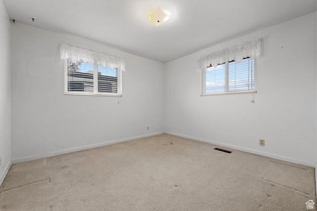 carpeted empty room featuring visible vents and baseboards