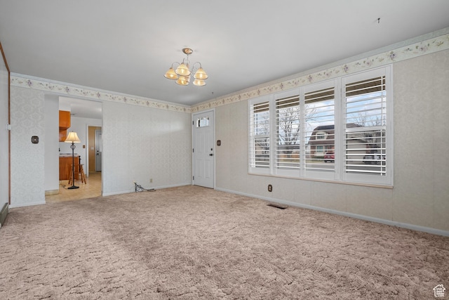 entryway with wallpapered walls, carpet, baseboards, and a chandelier