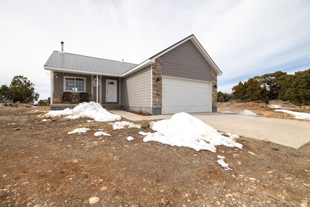 46501 W Bandanna Dr, Fruitland, UT 84027 - view of front of house with concrete driveway, covered porch, metal roof, a garage, and stone siding