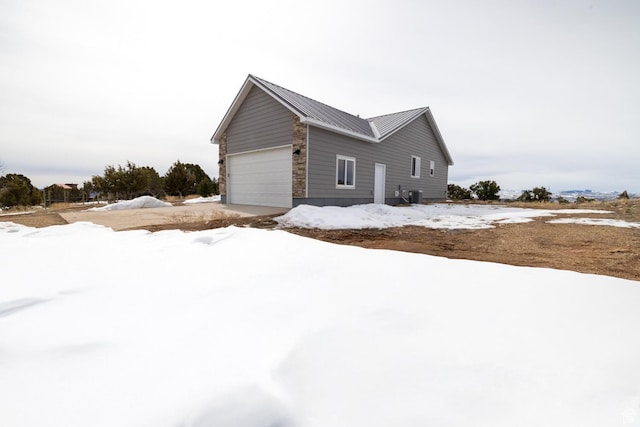 46501 W Bandanna Dr, Fruitland, UT 84027 - view of snowy exterior featuring an attached garage, central AC, and metal roof
