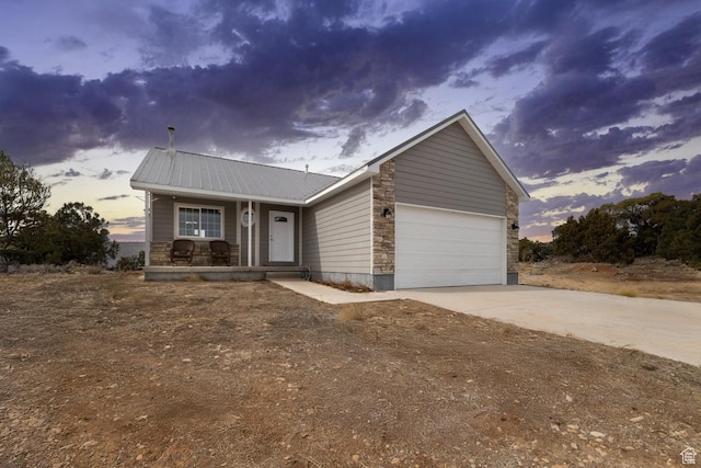 46501 W Bandanna Dr, Fruitland, UT 84027 - view of front of home featuring driveway, stone siding, a porch, an attached garage, and metal roof