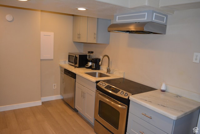 4023 W Severn Cir S, Jordan, UT 84009 - kitchen with appliances with stainless steel finishes, a sink, under cabinet range hood, light wood-type flooring, and baseboards