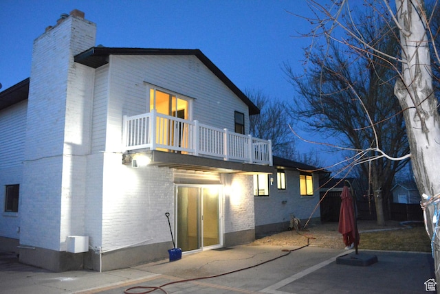 4023 W Severn Cir S, Jordan, UT 84009 - rear view of property featuring a balcony, a chimney, brick siding, and a patio