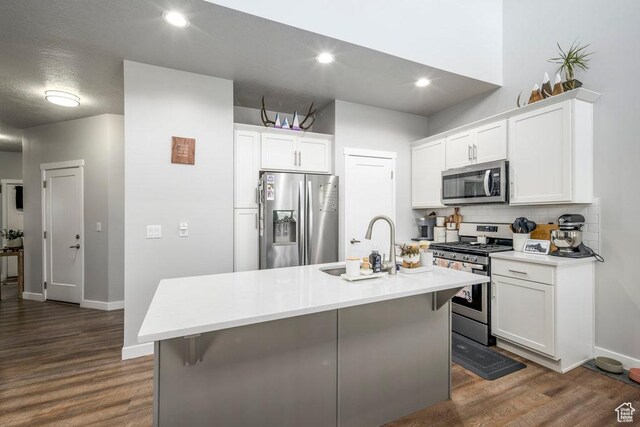 4268 S Steele Creek Ct E, Millcreek, UT 84107 - kitchen with appliances with stainless steel finishes, decorative backsplash, dark wood-type flooring, white cabinetry, and recessed lighting