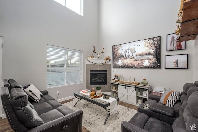 4268 S Steele Creek Ct E, Millcreek, UT 84107 - living area with wood finished floors, a tile fireplace, a towering ceiling, and baseboards