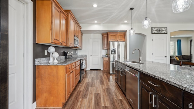 125 N 1430 E, Spanish Fork, UT 84660 - kitchen with stainless steel appliances, a sink, arched walkways, wood finished floors, and light stone countertops