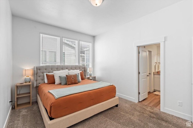 carpeted bedroom featuring ensuite bathroom and baseboards