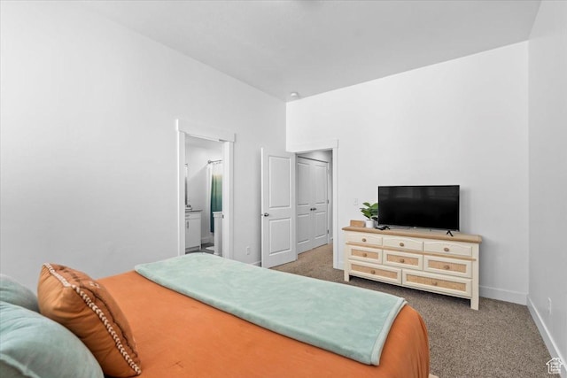 bedroom with connected bathroom, baseboards, and carpet flooring