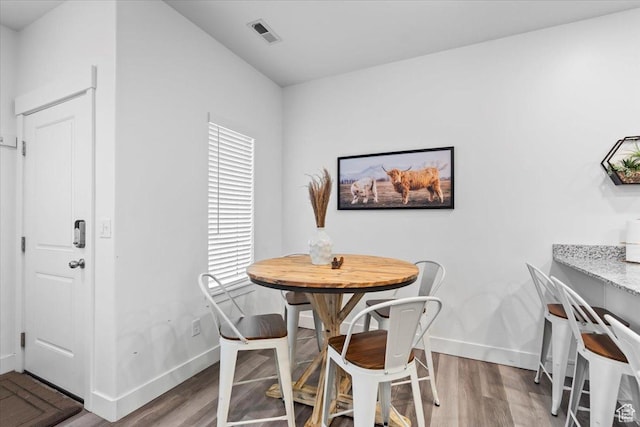 dining area featuring wood finished floors, visible vents, and baseboards