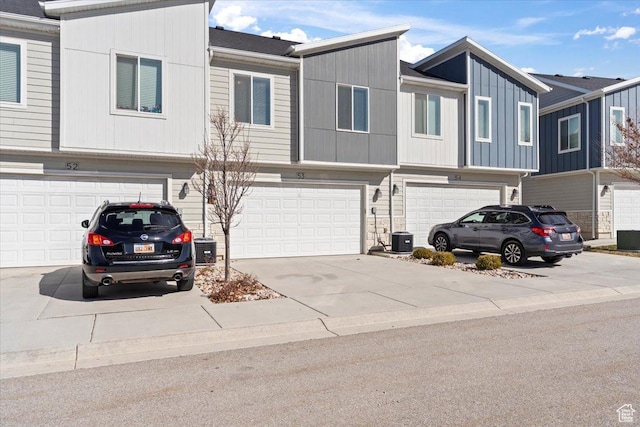 multi unit property with central AC unit, an attached garage, and driveway
