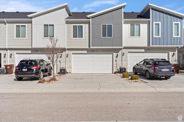 view of property with stone siding, driveway, a garage, and board and batten siding