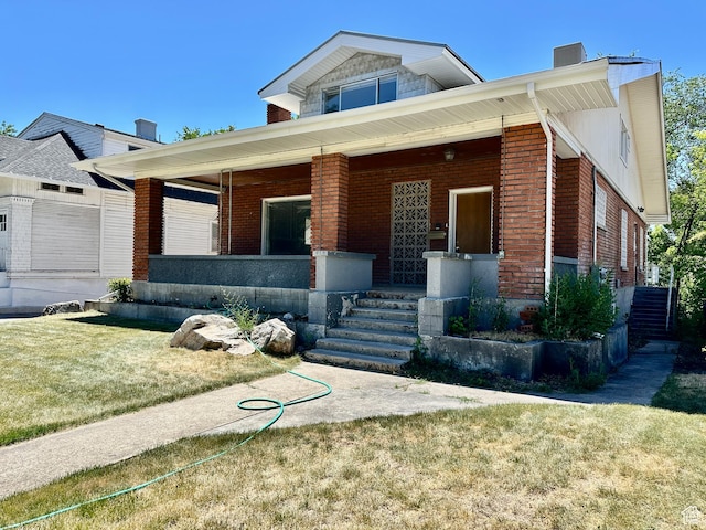 33 N 200 E, Logan, UT 84321 - view of front of house featuring covered porch, brick siding, and a front lawn