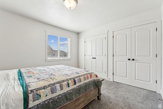 carpeted bedroom featuring multiple closets and a textured ceiling