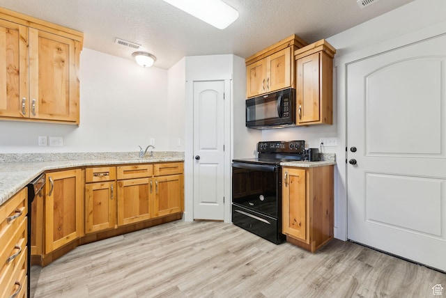 kitchen with visible vents, black appliances, light stone countertops, light wood-type flooring, and a textured ceiling