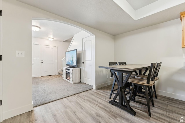 dining space featuring baseboards, arched walkways, and wood finished floors