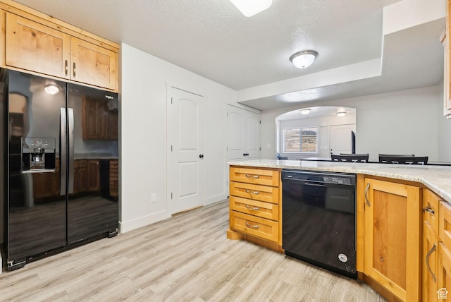 kitchen featuring light wood-type flooring, arched walkways, a textured ceiling, and black appliances