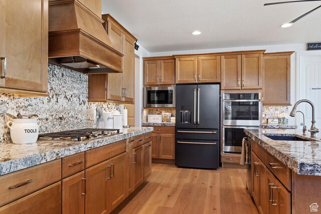 1251 N 2525 W, Clinton, UT 84015 - kitchen with light wood finished floors, custom exhaust hood, a sink, appliances with stainless steel finishes, and tasteful backsplash