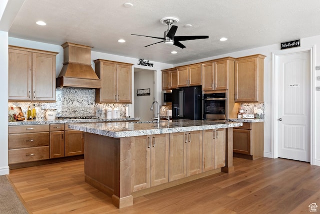 1251 N 2525 W, Clinton, UT 84015 - kitchen featuring ceiling fan, light wood-type flooring, an island with sink, custom range hood, and appliances with stainless steel finishes