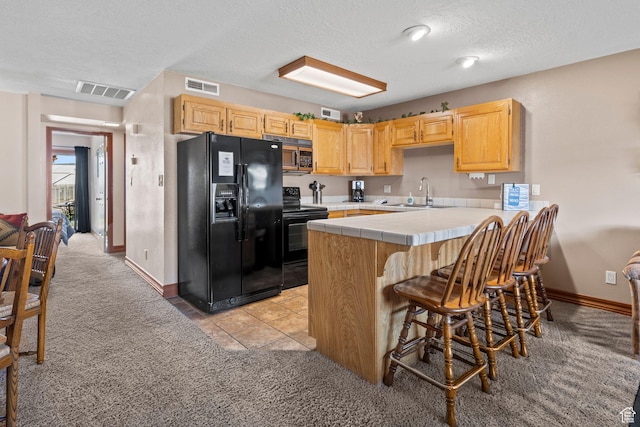 1845 W Canyon Dr S Unit 1610, St George, UT 84770 - kitchen with visible vents, a sink, black appliances, tile counters, and light colored carpet