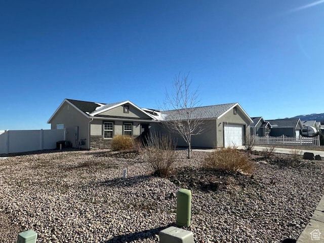 ranch-style home featuring fence, a garage, and stucco siding