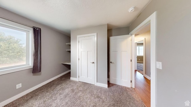 unfurnished bedroom with a closet, carpet flooring, a textured ceiling, and baseboards