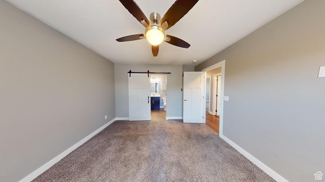 unfurnished bedroom with ensuite bath, carpet flooring, baseboards, and ceiling fan