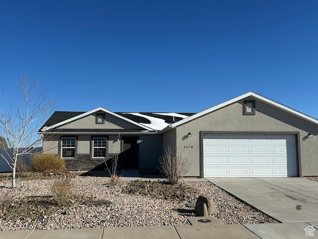 ranch-style home with stone siding, stucco siding, concrete driveway, and a garage