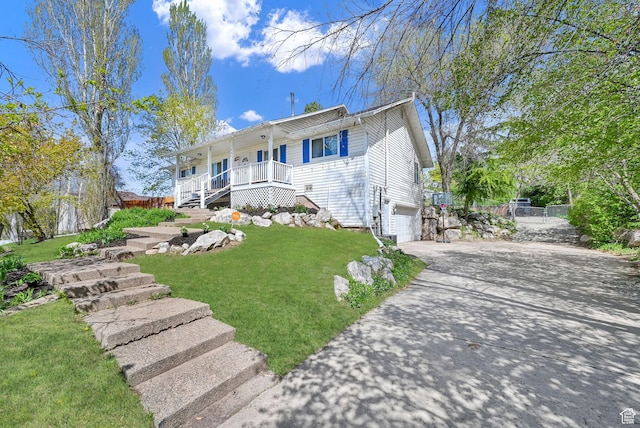 view of front facade with a front lawn, driveway, covered porch, an attached garage, and stairs