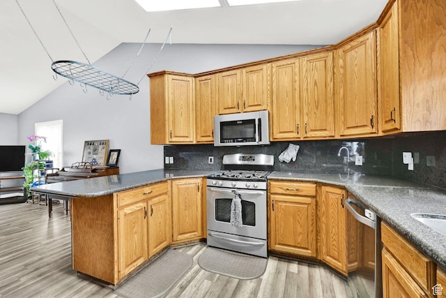 1461 E Antelope Dr, Layton, UT 84040 - kitchen with light wood finished floors, stainless steel appliances, a peninsula, tasteful backsplash, and vaulted ceiling