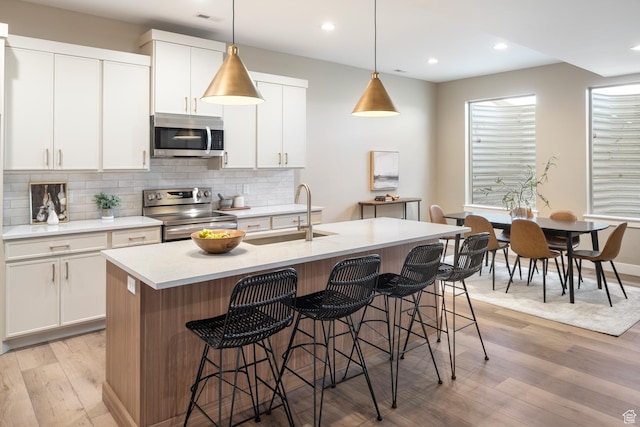 882 E 740 S, Salem, UT 84653 - kitchen with appliances with stainless steel finishes, a sink, tasteful backsplash, light wood finished floors, and a breakfast bar area