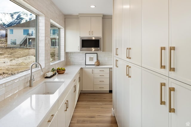 882 E 740 S, Salem, UT 84653 - kitchen featuring a sink, stainless steel microwave, light stone counters, light wood-type flooring, and backsplash