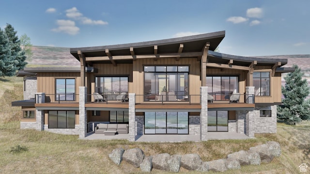 rear view of house with board and batten siding, stone siding, a balcony, and a patio