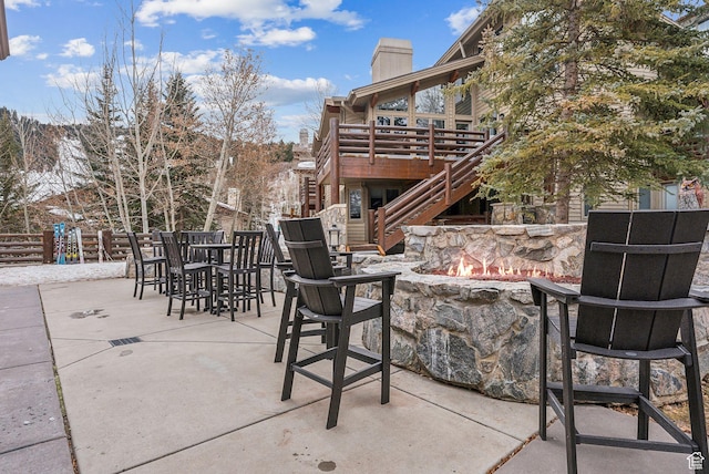 view of patio featuring fence, stairway, an outdoor fire pit, outdoor dining area, and a deck
