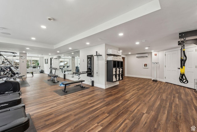exercise room with an AC wall unit, recessed lighting, wood finished floors, and baseboards